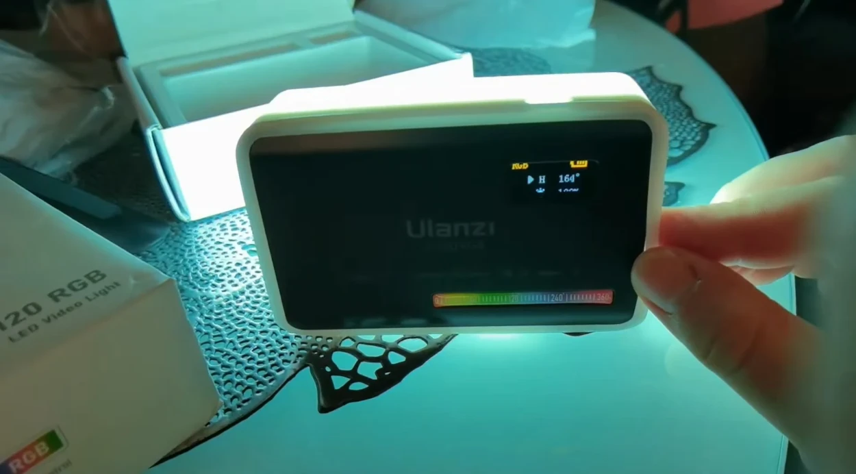 Панель Ulanzi VL120 RGB у надітому білому силіконовому дифузорі, що світиться бірюзовим відтінком 164 градуси з індикацією параметрів на екрані