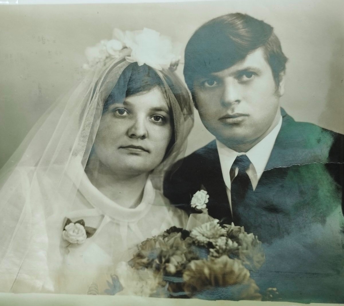 На фото подружня пара  Кухта Віктор і Галина (дівоче прізвище Войтюк). Весільна сукня нареченої та фата придбані у м. Хмельницький, на ринку. Весільний віночок виготовлений  з фатинових квітів. Костюм нареченого шерстяний фабричний.Сканкопію та позитив/фото надала для архіву    онука Михальчук Анастасія, 14 квітня 2026 року