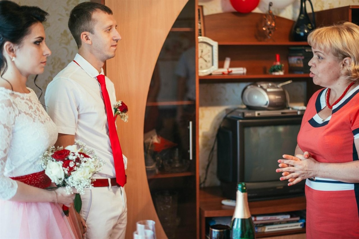 Людмила у своїй вітальні виголошує промову на весіллі доньки. Зараз кімната нежила - лише залишки вибитої віконної рами й уламки...
